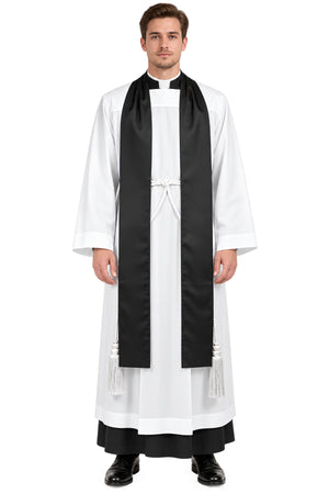 Front view of a clergyman wearing the Faithful Witness black clergy tippet over a white surplice, featuring a long flat black tippet with white braided waist cord and tassels.