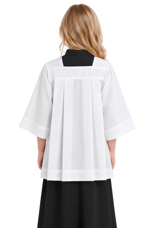 Young girl wearing a white square neck surplice over a black cassock, shown from the back with structured pleats, full sleeves, square yoke, and wide hem.
