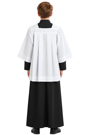 Young altar server wearing a white square neck surplice over a black cassock, shown from the back with four structured pleats, full sleeves, and square yoke.