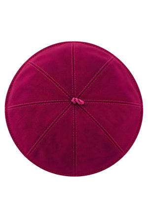 Top view of a magenta clergy zucchetto cap showing eight stitched fabric panels converging at the center crown loop.