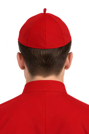 Back view of a person wearing a red clergy zucchetto cap with matching red clerical clothing, showing the fitted cap shape, stitched panel seams, and crown loop.