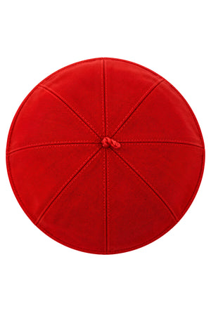 Top view of a red clergy zucchetto cap showing its eight stitched fabric panels converging at the center crown loop.
