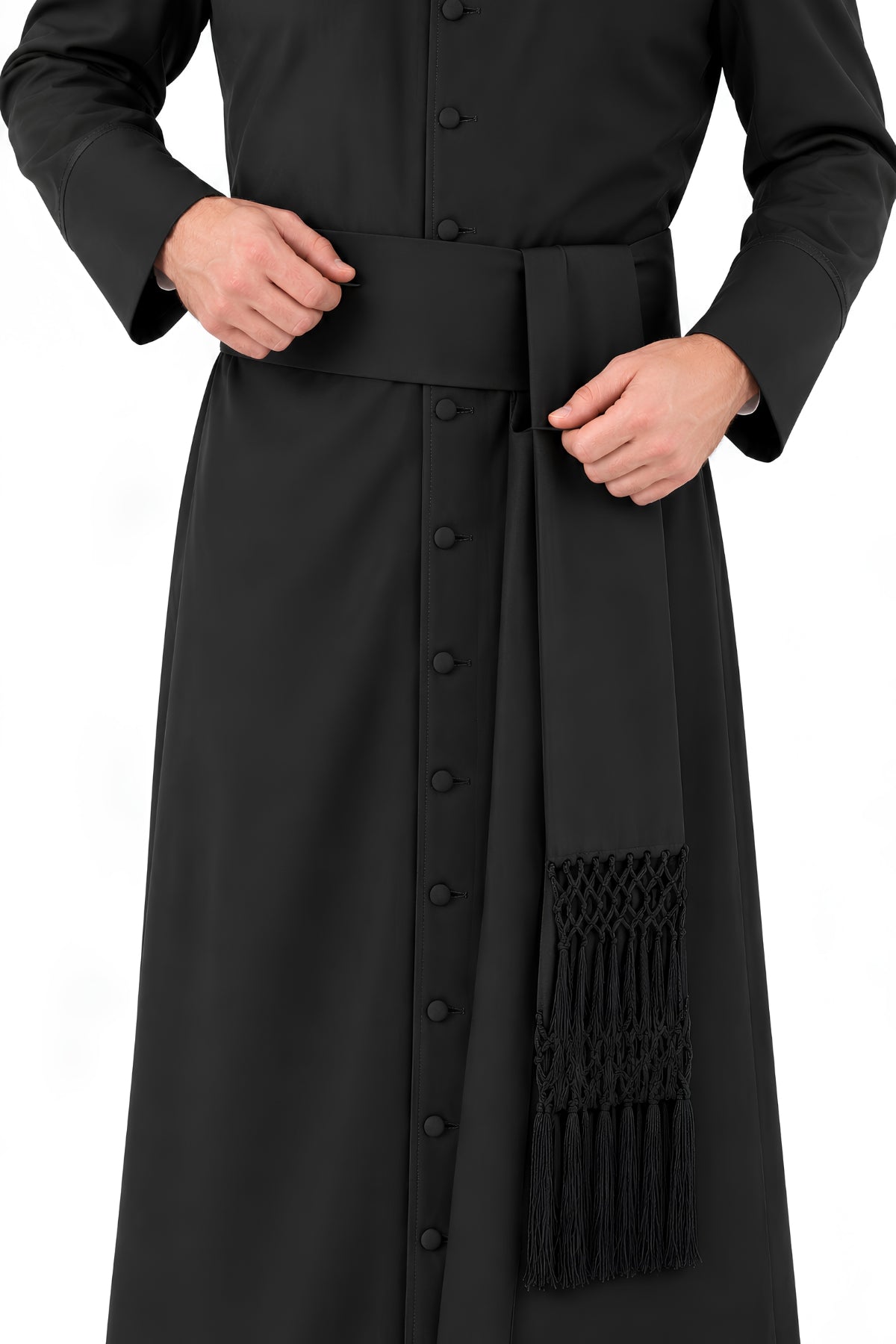Black Steadfast Devotion band cincture worn over a cassock, showing the wide waist sash, adjustable closure, and hand-knotted fringe detailing.